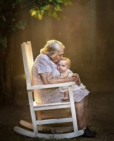 an old woman sitting in a rocking chair holding a baby