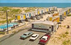 an aerial view of the beach with several buildings and cars parked in front