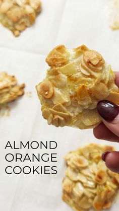 a hand holding up an orange cookie with almonds on it and the words almond orange cookies