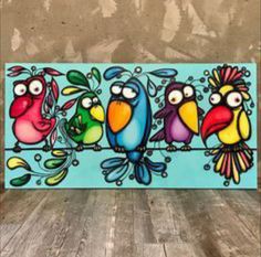 three colorful birds sitting on top of a wooden table