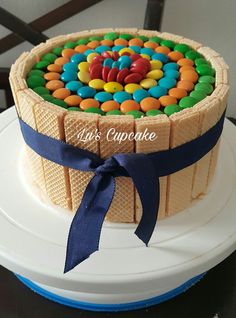 a cake decorated with colorful candies on top of a white plate and blue ribbon