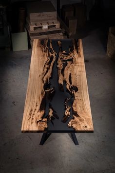 a table made out of wood with black paint on the top and legs, sitting in a warehouse