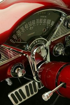 the gauges and dash board of a classic red sports car's dashboard are clearly visible