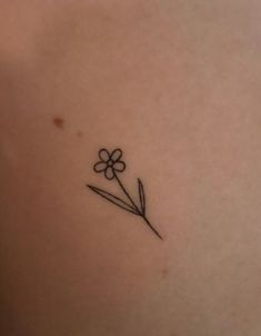 a small flower tattoo on the back of a woman's left side ribcage