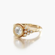 a gold ring with a diamond center and three small diamonds on the band, set against a white background