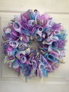 a purple and blue mesh wreath hanging on the front door with ribbons attached to it