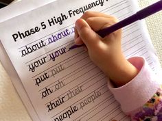 a child's hand writing on a piece of paper with the words phase 5 high frequency