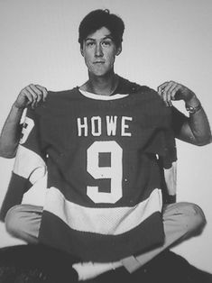 a man sitting on top of a black and white photo holding up a hockey jersey