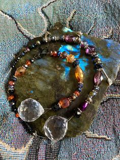 a piece of jewelry sitting on top of a blue and green cloth covered surface with beads