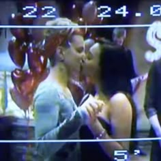 two people kissing each other in front of balloons and numbers on the wall behind them