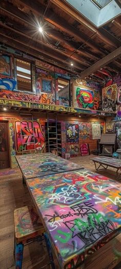 the room is covered in graffiti and has tables, benches, and couches for seating