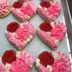 heart shaped cookies decorated with pink and red icing on a baking sheet in the shape of hearts