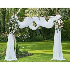 an outdoor wedding ceremony setup with white flowers and draping on the arbors