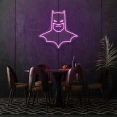 a purple neon batman sign on the wall above a dining room table with four chairs