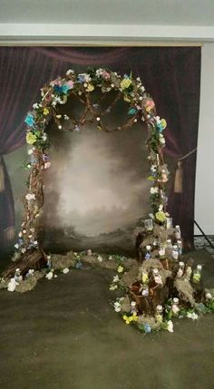 an arch made out of flowers and branches in front of a painting on the wall