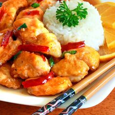 a white plate topped with chicken and rice next to chopsticks