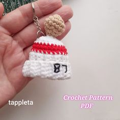 a crochet keychain with a hat on it is being held by someone's hand