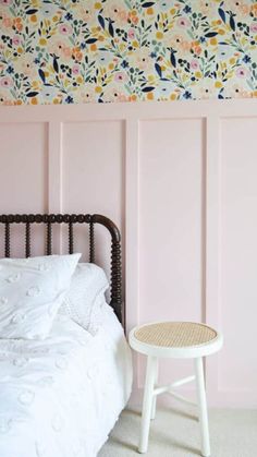 a white bed sitting next to a pink wall with flowers painted on the walls above it