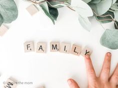 the word family spelled with scrabbles on a white surface surrounded by greenery