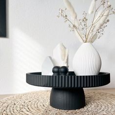 two white vases sitting on top of a round table