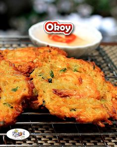 three fried food items on a cooling rack next to a bowl of yogurt