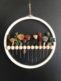 a cross stitch pattern with flowers and leaves on the inside of a hoop hanging from a wall