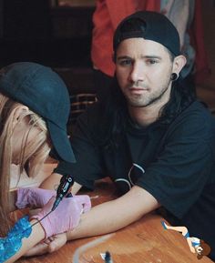 a man and woman sitting at a table with one holding the other's arm