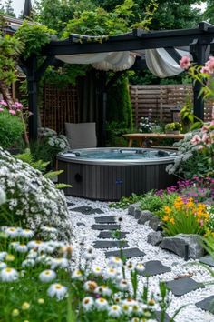 an outdoor hot tub surrounded by plants and flowers