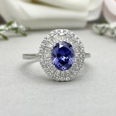 This beautiful ring is made from genuine 925 sterling silver with rhodium plating.Ring details--The Main stone is an oval cut 8mm by 6mm Lab Created Tanzanite Stone-Side stones are 2mm by 1mm Baguette simulated diamonds and Round 1.2mm Simulated Diamonds -Ring is casted in solid 925 sterling silver with rhodium plating (yellow gold and rose gold plated also available, please check the drop down menu for more options)-The Total face height of the ring measures 11mms and the band width measures 2m Baguette Cut Halo Ring For Anniversary, Silver Baguette Cut Wedding Ring With Halo Setting, Silver Baguette Cut Ring With Halo Setting, Silver Sapphire Ring With Halo Design For Anniversary, Silver Marquise Halo Ring For Anniversary, Silver Sapphire Ring With Baguette Cut And Halo Setting, Silver Oval Sapphire Wedding Ring, Silver Baguette-cut Ring With Halo Design, Oval Silver Sapphire Wedding Ring