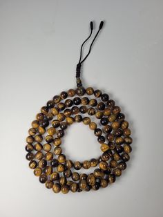 A Tiger Eye mala in Buddhism is a traditional prayer tool composed of Tiger Eye beads, known for their brown/black color. With 108 beads and a guru bead, it aids practitioners in meditation and mantra recitation, fostering focus and spiritual connection. The Tiger Eye mala is revered for its beauty and spiritual significance, symbolizing wisdom, inner peace, and the path to enlightenment in Buddhist practice. Comes with a beautiful silk bag. Size 7mm diameter. The size, color, and color of the bag may vary. Metal mala counters and ten thousand boom counters are optional. Path To Enlightenment, Buddhist Practices, Silk Bag, 108 Bead, Tiger Eye Beads, Eye Beads, A Tiger, Spiritual Connection, The Tiger