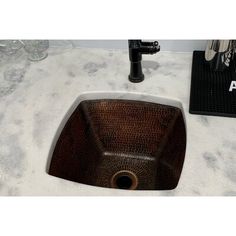 a brown sink sitting on top of a counter next to a black faucet