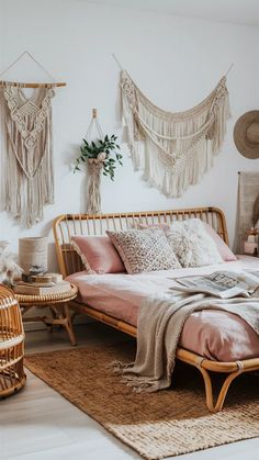 a bed with pink sheets and pillows in a room next to wicker chairs, rugs and wall hangings