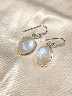 These gemstone dangle earrings are set with ethereal moonstone, fashioned into large smooth oval cabochons and set in sterling silver. 1.25" long. More beautiful moonstone found here! Round Moonstone Cabochon Earrings, Silver Oval Cabochon Earrings, Elegant Oval Nickel-free Moonstone Ring, Elegant Oval Moonstone Nickel-free Ring, Handmade Oval Moonstone Earrings, Oval Moonstone Earrings For Gift, White Oval Moonstone Earrings, Ethereal Jewelry, Cabochon Earrings