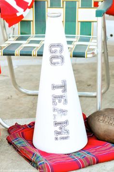 a white cone sitting on top of a blanket next to a football and a chair