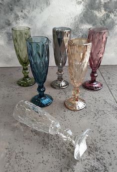 five different colored glass goblets sitting next to each other on a counter top