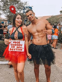 a man and woman dressed in costumes posing for a photo at an outdoor event with other people