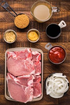 raw meats and sauces laid out on a wooden table with ingredients for the recipe