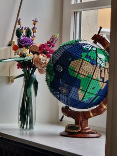 a vase filled with flowers sitting on top of a window sill next to a globe