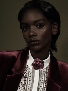 a woman in a red jacket and white shirt with a flower on her lapel