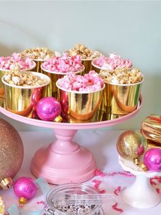 pink and gold cupcakes are sitting on a cake platter next to other decorations