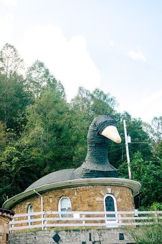 an old stone building with a large bird's head on the roof and fence around it