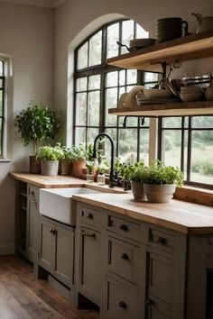 a kitchen filled with lots of windows next to a wooden counter top and white cabinets