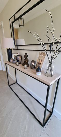 a console table with vases and pictures on it in front of a large mirror