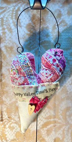 a valentine's day hat hanging from a hook on a wooden wall with sunglasses