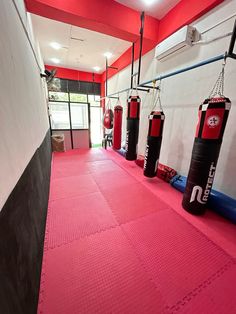 a gym with pink flooring and red punching bags on the wall next to each other