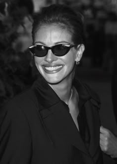 a woman wearing sunglasses and smiling for the camera