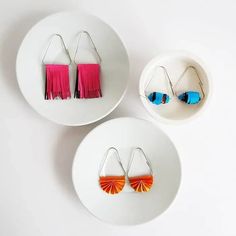 three white plates with colorful earrings on them