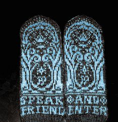 two knitted mittens sitting next to each other on top of a black surface