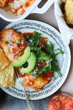 a white plate topped with food next to a bowl of salsa and tortilla chips