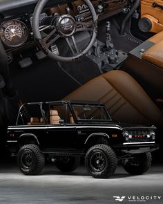 the interior of a black jeep with tan leather upholstered seats and steering wheel